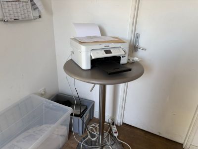 une imprimante posée sur une table, à côté d'une poubelle