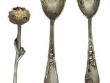 three silver spoons and a spoon with a flower on them