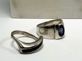 pair of silver rings with a blue stone sitting on a white surface