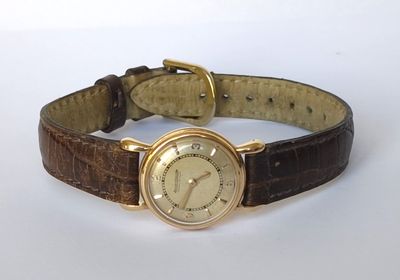une photo d'une montre-bracelet en or avec un bracelet en cuir marron