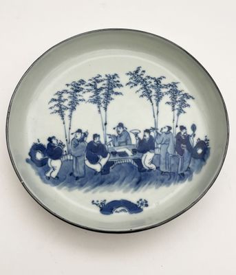 a blue and white plate with a picture of a group of people on it