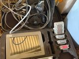 un ordinateur portable et d'autres appareils électroniques dans une mallette posée par terre