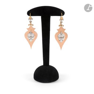 a pair of earrings on a black stand with a white background