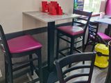 tables and chairs in a restaurant with pink chairs and a yellow trash can