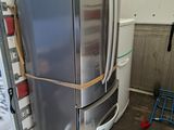 a large silver refrigerator in a room with a ladder