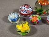 five glass marbles with flowers in them on a table