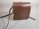 brown leather camera case on white surface with black cord