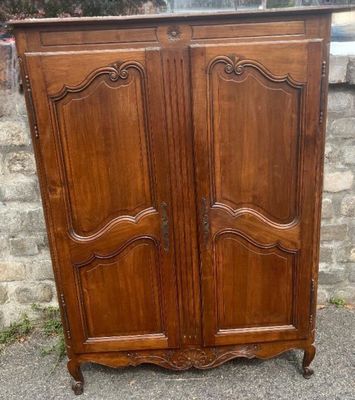 an antique wooden armoire with two doors and a drawer