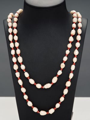 un collier de perles blanches et rouges sur un mannequin noir