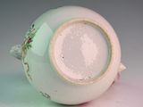 a white vase with a green and pink decoration on it