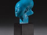 une sculpture bleue représentant une tête d'homme, posée sur un socle noir