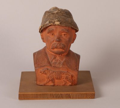 statue d'un homme coiffé d'un chapeau, posée sur un socle en bois