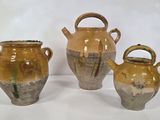 trois vases marron posés sur une surface blanche, sur fond blanc