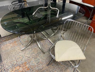 une table en verre avec un piètement en métal et des chaises dans une pièce