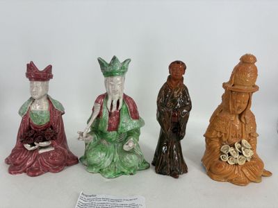 Trois figurines représentant des personnages asiatiques sont posées sur une table.