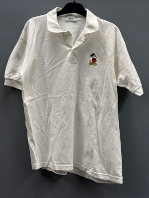 un polo blanc avec un écusson de Mickey Mouse sur la poitrine