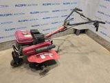 a red lawn mower sitting on top of a cement floor next to a wall