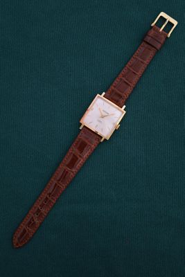 a watch on a green surface with a brown strap