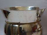 a silver bowl with a chain around it on a white surface