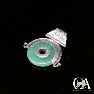une photo d'un pendentif en argent et en jade orné d'un œil vert