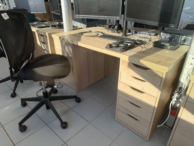 a desk with two monitors and a chair in front of it