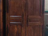 une armoire en bois posée à côté d'une chaise dans une pièce