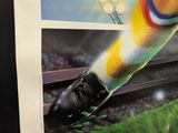 a poster of a soccer player kicking a ball on the field