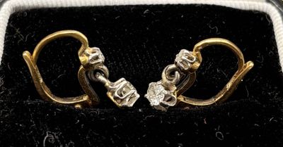 a pair of gold and diamond earrings in a black velvet case