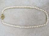 a picture of a white pearl necklace with a gold clasp