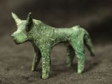 a small green statue of a dog on a brown surface