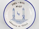 une assiette bleue et blanche sur laquelle est représenté un phare