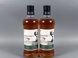 deux bouteilles de whisky posées l'une à côté de l'autre sur une surface grise