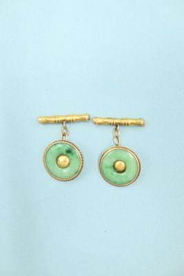 a pair of green and gold earrings on a blue background