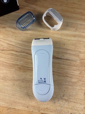 un rasoir électrique blanc posé sur une table à côté d'un téléphone portable