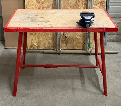 une table rouge sur laquelle est posé un morceau de bois