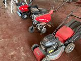 two lawn mowers that are sitting in a garage
