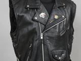 un gilet en cuir noir posé sur un présentoir à mannequin, devant un fond blanc