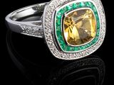 un gros plan d'une bague sertie d'une topaze jaune et rehaussée d'émeraudes