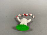a toy of a person laying on the ground with a green frisbee