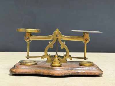 an antique brass scale on a wooden base with a black background