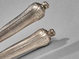 two silver spoons sitting on a table next to each other