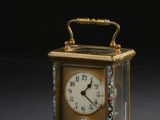une petite horloge munie d'une poignée, posée sur un fond noir