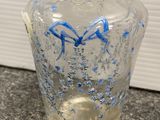 a clear glass bottle with blue and white designs on it