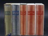 four books are lined up in a row on a black surface