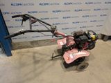 an image of a pink lawn mower parked in front of a blue wall