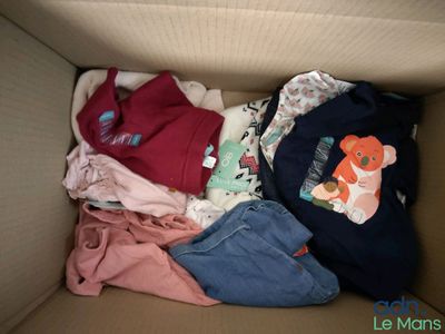 une boîte en carton remplie de vêtements et d'un ours en peluche