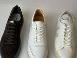 four pairs of white, black, and brown sneakers lined up on a white surface