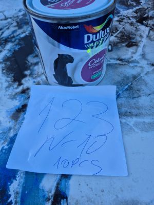 un pot de peinture posé par terre à côté d'une feuille de papier