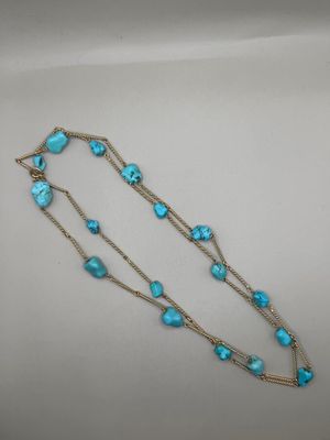 un gros plan d'un collier composé de perles de turquoise sur un fond blanc