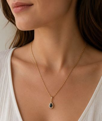 une femme portant une chemise blanche et un collier en or orné d'une pierre noire